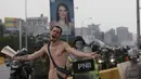 Seorang demonstran berteriak saat unjuk rasa di Caracas, Venezuela (20/4). Di tengah bentrokan seorang demonstran bugil dan maju menghadang petugas. (AP Photo/Fernando Llano)