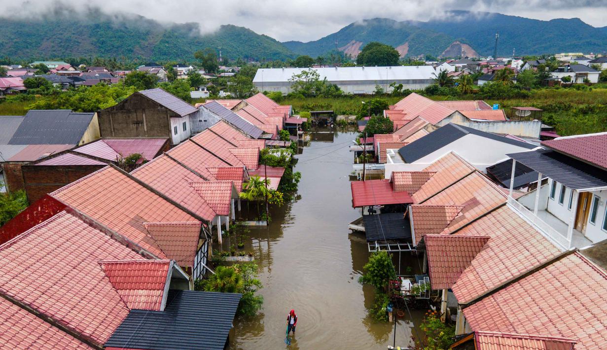 Foto udara menunjukkan seorang pria melintasi banjir setelah hujan deras di permukiman Darul Imarah di pinggiran Banda Aceh pada Kamis 27 November 2025. Curah hujan tinggi yang dipicu siklon tropis menyebabkan sejumlah wilayah di Aceh Besar, termasuk Darul Imarah, terendam banjir. (CHAIDEER MAHYUDDIN/AFP)