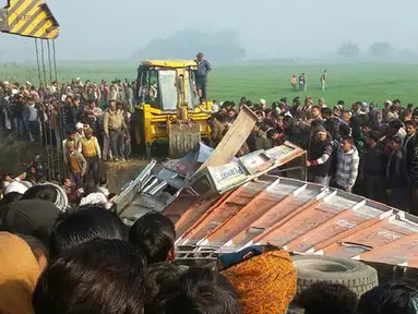 Sejumlah orang berkumpul di lokasi kecelakaan antara bus sekolah dan truk di Etah, negara bagian Uttar Pradesh, India, Kamis (19/1). Dalam tragedi tersebut sedikitnya 15 anak dan pengemudi bus tewas serta puluhan lainnya terluka. (AFP PHOTO/STR)