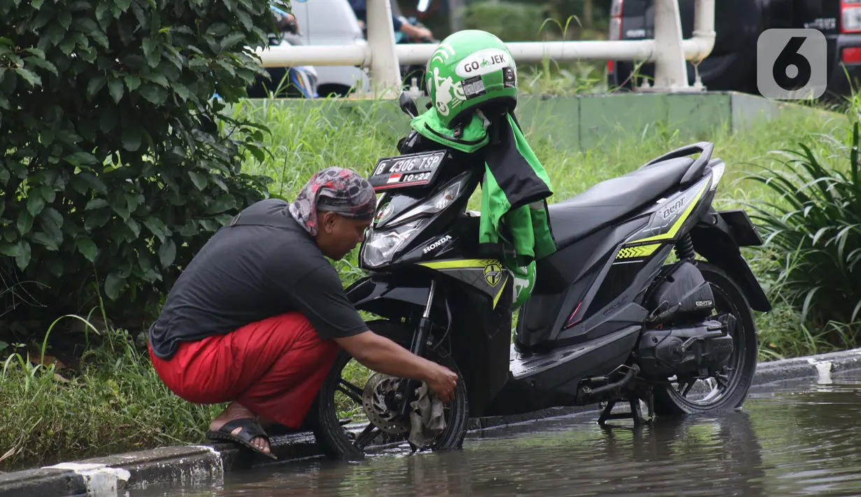 Pengendara memanfaatkan genangan air untuk mencuci kendaraan di Jalan HBR Motik Kemayoran, Jakarta, Selasa (25/2/2020). Hujan yang mengguyur Jakarta sejak Senin (24/2) malam membuat sejumlah kali meluap dan menyebabkan banjir. (Liputan6.com/Helmi Fithriansyah)