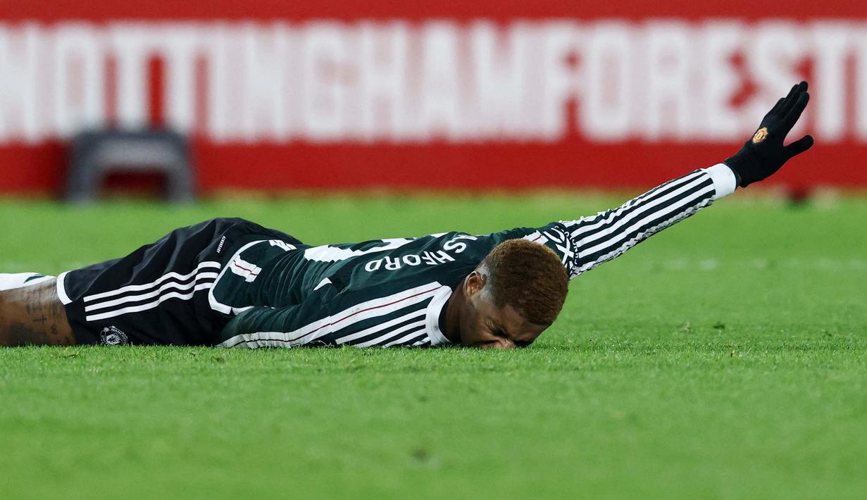 Pemain Manchester United, Marcus Rashford, terkapar saat melawan Nottingham Forest pada laga pekan ke-20 Premier League 2023/2024, Minggu (31/12/2023) dini hari WIB. MU takluk dengan skor 1-2. (AFP/Darren Staples)