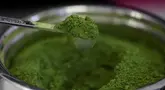 Sam Butarbutar mengambil sesendok matcha dari wadah sambil membuat minuman matcha di Third Culture, Berkeley, California, Amerika Serikat pada 15 Juli 2025. (Justin Sullivan/Getty Images North America/Getty Images via AFP)