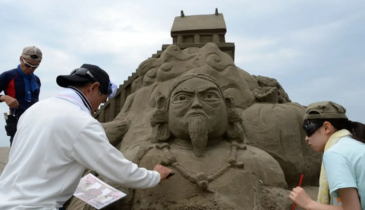 Seniman patung pasir berusaha menyelesaikan karya mereka yang diberi nama "Nihon Shoki" atau "The Chronicles of Japan" yang akan dipamerkan dalam Asahi Sand Sculpture di pantai Yasashigaura, Asahi, Chiba, (13/7/2014). (AFP PHOTO/Toshifumi Kitamura)