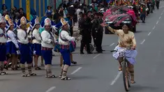 Seorang wanita melambaikan tangan saat mengikuti balapan sepeda Cholita di El Alto, La Paz, Bolivia (12/11). Dalam balapan sepeda ini peserta mengenakan topi bundar, rok dan selendang sulaman. (AP Photo / Juan Karita)