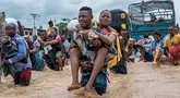 Les résidents portent une femme tandis que d'autres traversent le déluge dans le district de Ndjili, Kinshasa, le 6 avril 2025. (Hardy Bope / AFP)