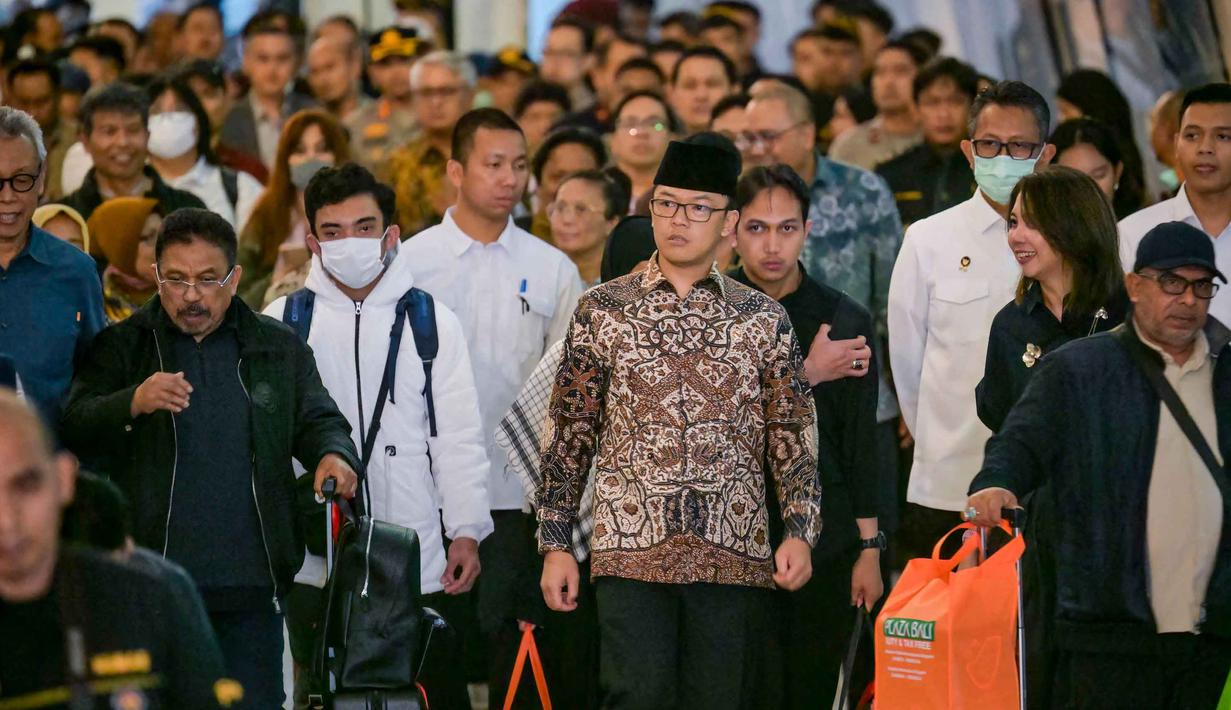 Menteri Luar Negeri, Sugiono (tengah), hadir langsung untuk memantau proses kedatangan serta memastikan kondisi para WNI yang baru tiba. Tampak dalam foto, Menteri Luar Negeri Indonesia, Sugiono (tengah), berjalan bersama Warga Negara Indonesia yang kembali dari Iran tiba di Bandara Internasional Soekarno-Hatta, Tangerang, Banten, pada Selasa 10 Maret 2026. (BAY ISMOYO/AFP)