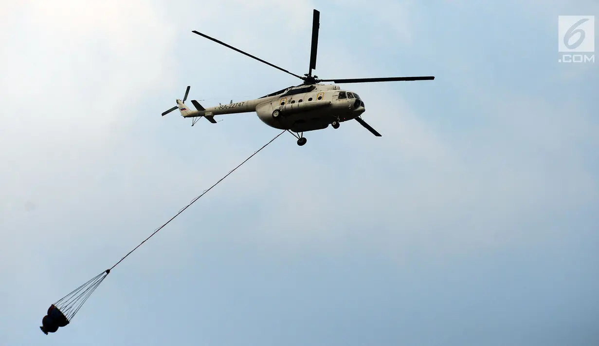 Helikopter water bombing membawa air untuk disiramkan ke arah ban yang dibakar massa di kawasan Slipi, Jakarta, Rabu (22/5/2019). Air dijatuhkan dari udara ke arah api yang berasal dari ban bekas. (merdeka.com/Imam Buhori)