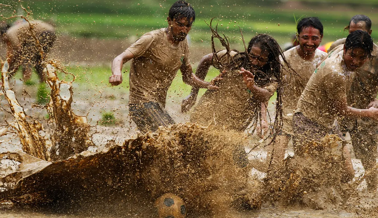 Sejumlah pria Nepal bermain bola di lumpur pada Asar Pandra, atau hari menanam padi nasional di Lalitpur, 29 Juni 2018. Asar Pandra diadakan sebagai tanda dimulainya kembali aktivitas tanam padi di sawah saat musim hujan tiba. (AP Photo/Niranjan Shrestha)