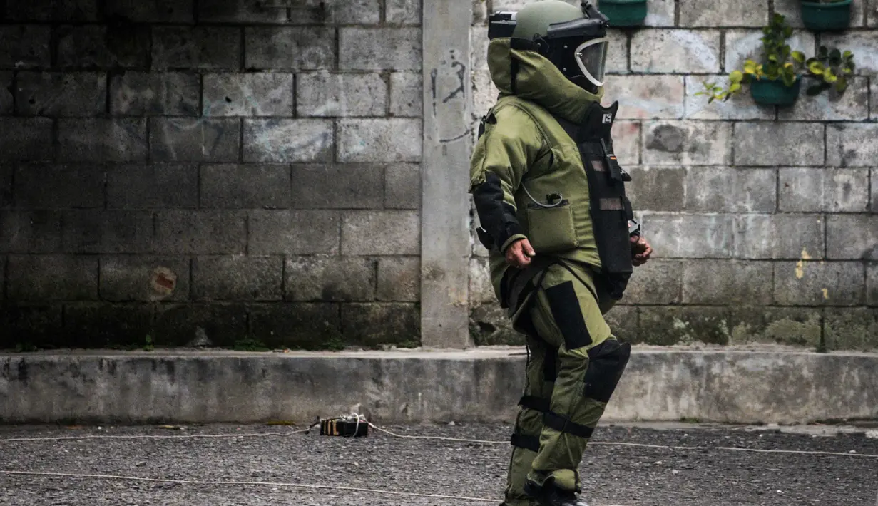 Benda mencurigakan tersebut ditemukan pertama kali oleh warga sekitar pukul 08.30 WIB. Tampak dalam foto, seorang petugas polisi dari unit penjinak bom memeriksa sebuah benda mencurigakan berbentuk kotak yang dibungkus lakban hitam dengan kabel di depan Gereja Kristen Protestan Simalungun (GKPS) di Bandung, Jawa Barat pada Jumat 19 Desember 2025. (Timur Matahari/AFP)