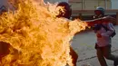 Seorang demonstran berlari saat tubuhnya terbakar disela unjuk rasa yang diwarnai bentrokan menentang Presiden Venezuela, Nicolas Maduro di Caracas, Rabu (3/5). Pria itu tersulut api dari ledakan tangki sepeda motor milik polisi. (RONALDO SCHEMIDT / AFP)