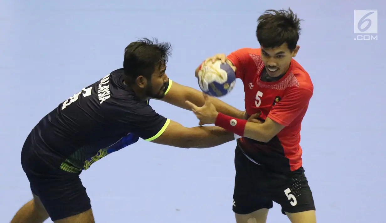 Pemain bola tangan Indonesia, Fitra Agung Aditya P (kanan) mencoba lolos dari kawalan pemain Malaysia pada penyisihan grup 3 bola tangan Asian Games 2018 di GOR PP POPKI, Jakarta, Minggu (26/8). Indonesia unggul 31-22. (Liputan6.com/Helmi Fithriansyah)