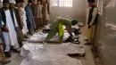 Seorang pria berdiri dekat mayat kerabtanya yang tewas, di sebuah rumah sakit di kota Herat, Afghanistan, Selasa (6/6). Sebuah bom sepeda motor meledak di luar sebuah masjid bersejarah dan menyebabkan tujuh orang tewas. (AP Photos/Hamed Sarfarazi)