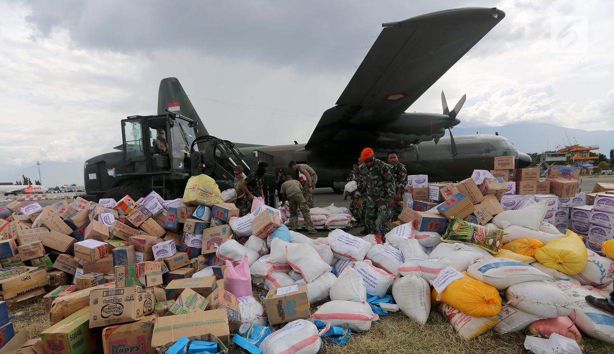 Prajurit TNI dibantu tentara Amerika Serikat mendistribusikan bantuan logistik yang tiba di Bandara Mutiara Sis Al-Jufri, Palu, Sulawesi Tengah, Minggu (7/10). Bantuan asing tiba menggunakan pesawat Hercules. (Liputan6.com/Fery Pradolo)