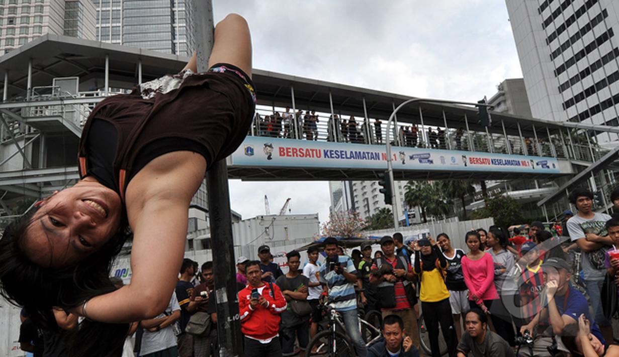 Tiang rambu lalu lintas menjadi arena aksi dari pegiat 'Pole Dance'  di Bundaran HI, Jakarta, Minggu (18/1/2015). (Liputan6.com/Miftahul Hayat)