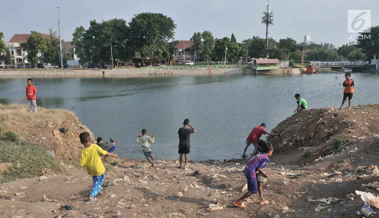 Anak-anak bermain di pinggir Waduk Ria Rio di kawasan Pedongkelan, Jakarta, Kamis (11/7/2019). Meski bertempat tinggal di atas lahan sengketa, anak-anak setempat memanfaatkan tanah kosong yang penuh semak belukar tersebut sebagai sarana bermain ketika sore hari. (merdeka.com/Iqbal S. Nugroho)