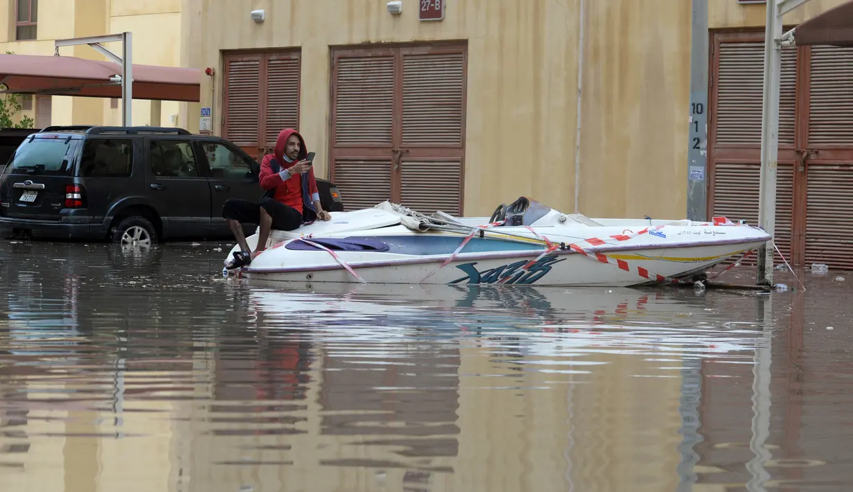 Seorang pria duduk di atas perahu di sebuah jalan yang terendam banjir menyusul hujan lebat di Kegubernuran Mubarak Al-Kabeer, Kuwait (29/11/2020). Hujan lebat melanda Kuwait pada Sabtu (28/11) malam dan Minggu (29/11) pagi waktu setempat. (Xinhua/Asad)