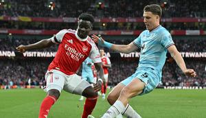 Bukayo Saka mencoba menggocek pemain Burnley. (Glyn KIRK / AFP)