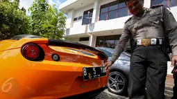 Petugas menunjukan mobil mewah berplat nomor palsu di Kantor Satlantas Jakarta Utara, Kamis (28/5/2015). Satlantas Jakarta Utara berhasil mengamankan beberapa unit mobil mewah yang diduga bodong. (Liputan6.com/Faizal Fanani)