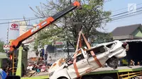 Petugas derek mengevakuasi bangkai mobil kecelakaan maut yang hancur tertindih badan truk muatan tanah di Karawaci, Tangerang, Kamis (1/8/2019). Lima orang penumpang minibus menjadi korban, empat diantaranya meninggal dan satu balita berhasil diselamatkan warga. (Liputan6.com/Pramita Tristiawati)