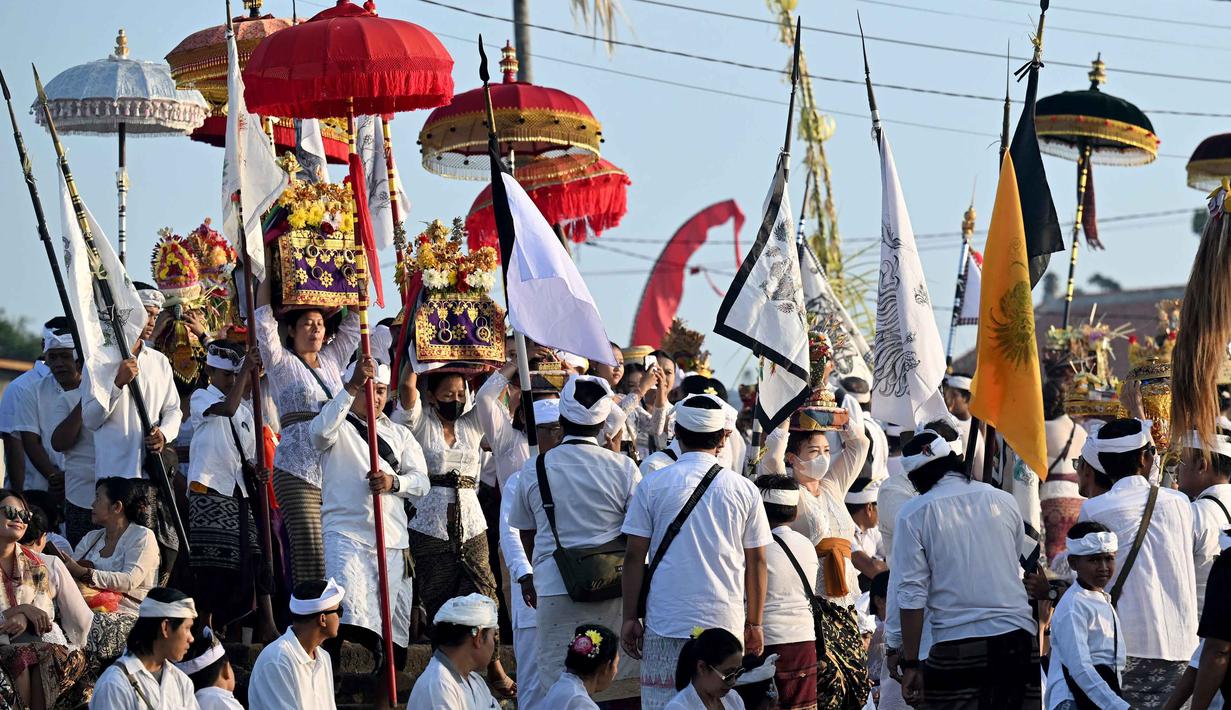Sejak dini hari, umat Hindu Bali sudah bergerak menuju pantai dengan membawa berbagai sarana upacara, seperti pralingga, palawatan berupa barong dan rangda, umbul-umbul hingga kober. Tampak dalam foto, umat Hindu saat mengikuti upacara doa Melasti di salah satu pantai di Denpasar, Bali, pada Senin 16 Maret 2026. (SONNY TUMBELAKA/AFP)