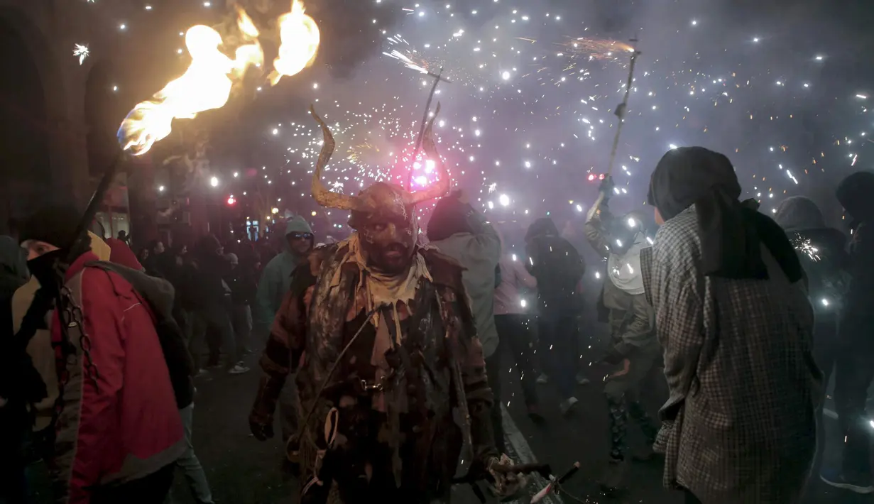 Seorang warga berpakaian seperti hantu dengan memegang tongkat kembang api selama perayaan " Correfocs ", Mallorca, Spanyol, (24/1). Orang - orang menari sambil men yalakan kembang api diantara kerumunan. (REUTERS / Enrique Calvo)