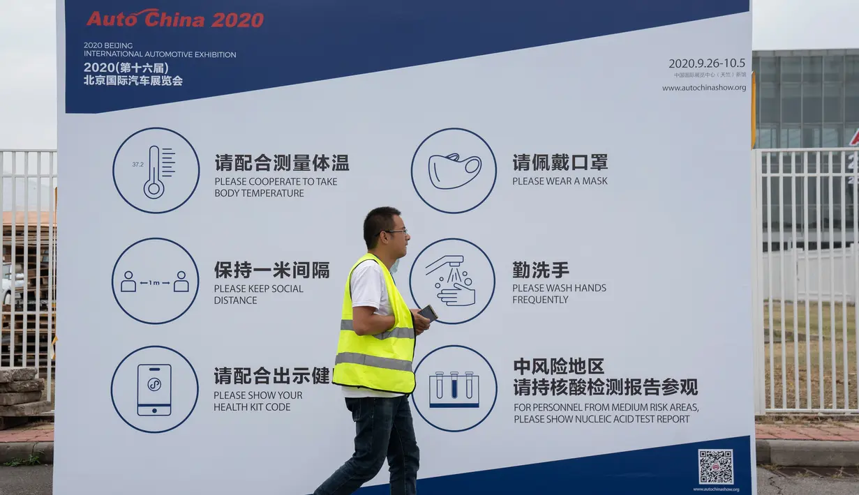 Pekerja melewati papan informasi mencegah penyebaran Covid-19 untuk peserta pameran Auto China 2020 di Beijing, Kamis (24/9/2020). Ajang Beijing International Automotive Exhibition 2020 (Auto China 2020) digelar mulai 26 September 2020 - 5 Oktober 2020 mendatang. (AP Photo/Ng Han Guan)