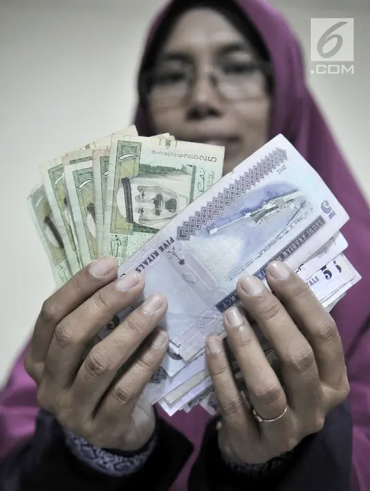 Calon jemaah haji menunjukkan  mata uang riyal di Asrama Haji Pondok Gede, Jakarta, Senin (22/7/2019). Para calon jemaah haji menukarkan uang rupiah ke riyal sebelum bertolak ke Tanah Suci. (merdeka.com/Iqbal Nugroho)