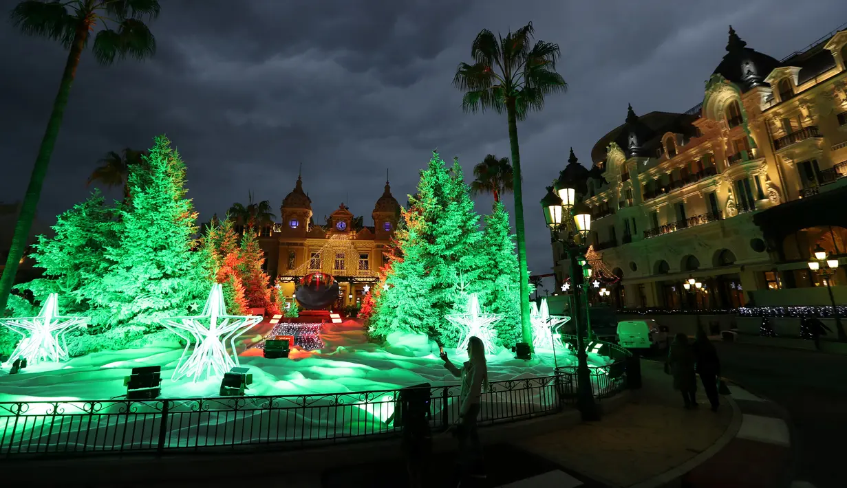 Seorang wanita mengambil gambar lampu dan dekorasi menyambut Natal yang menghiasi depan Kasino Monte-Carlo di Monako pada 7 Desember 2018. (Photo by VALERY HACHE / AFP)