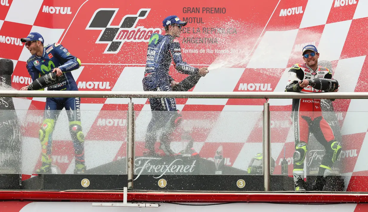 Dua pembalap Movistar Yamaha, Maverick Vinales dan Valentino Rossi serta pembalap LCR Honda, Cal Crutchlow membuka sampanye di atas podium MotoGP Argentina, Minggu (9/4). Vinales keluar sebagai pemenang MotoGP Argentina. (AP Photo/Nicolas Aguilera)