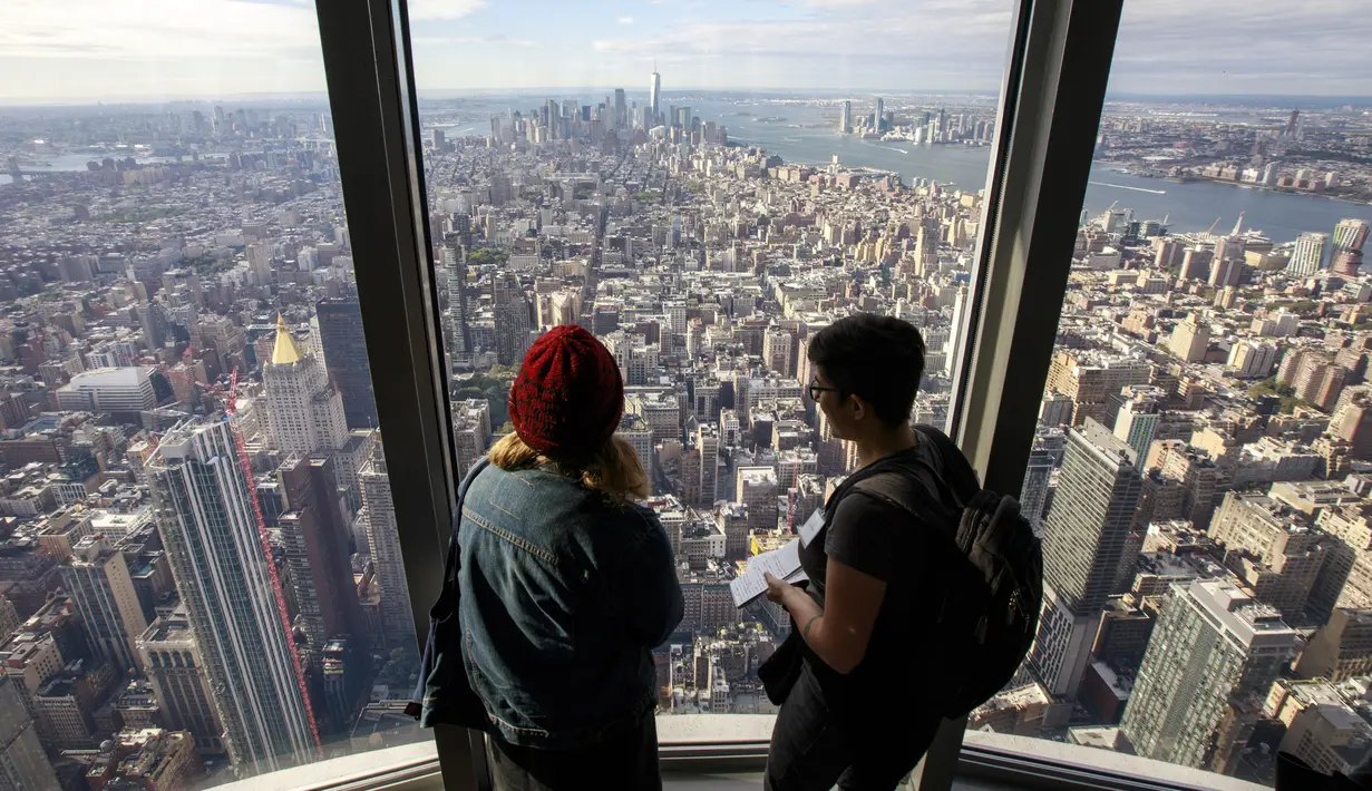 Pengunjung menikmati pemandangan Kota Manhattan dari ruangan observatorium di lantai 102 Gedung Empire State yang baru direnovasi di New York (10/10/2019). Dibuka untuk umum pada 12 Oktober, ruang observatorium ini berjarak 1.250 kaki di atas permukaan jalan. (AFP Photo/Drew Angerer)