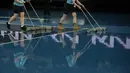 Staf mengeringkan lapangan saat hujan menunda pertandingan perempat final kejuaraan tenis Australia Open 2023 di Melbourne, Selasa (24/1/2023). Ball boy dan staf lapangan menggunakan alat pengering hingga lap tangan bergotong-royong mengeringkan lapangan dari sisa hujan yang menggenang. (AP Photo/Aaron Favila)