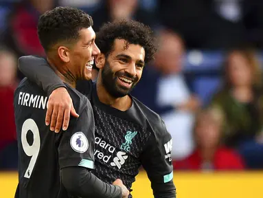 Striker Liverpool, Roberto Firmino, melakukan selebrasi bersama Mohamed Salah usai membobol gawang Burnley pada laga Premier League 2019 di Stadion Turf Moor, Sabtu (31/8). Liverpool menang 3-0 atas Burnley. (AP/Anthony Devlin)