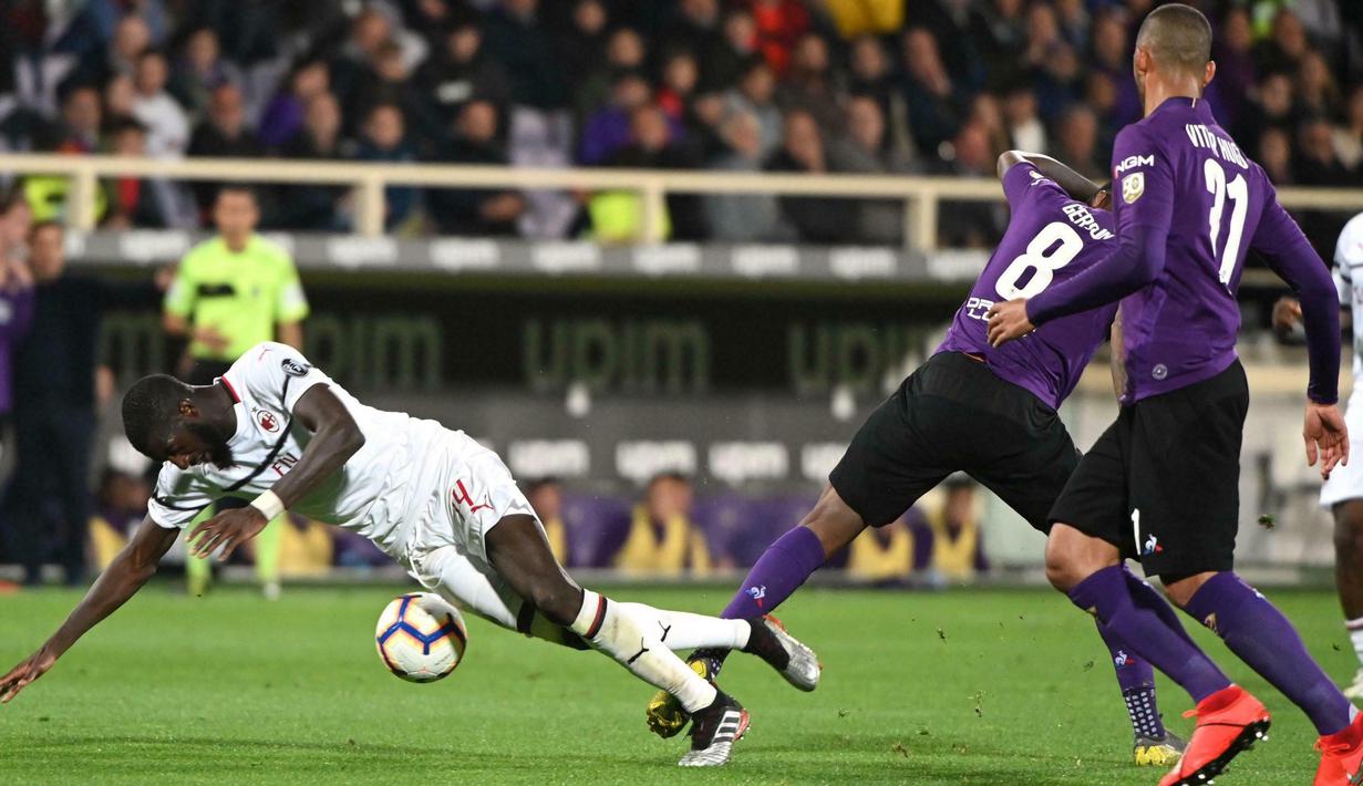 Gelandang AC Milan, Tiemoue Bakayoko, terjatuh saat berebut dengan pemain Fiorentina, Gerson, pada laga Serie A di Stadion Artemio Franchi, Sabtu (11/5). AC Milan menang 1-0 atas Fiorentina. (AP/Claudio Giovanni)