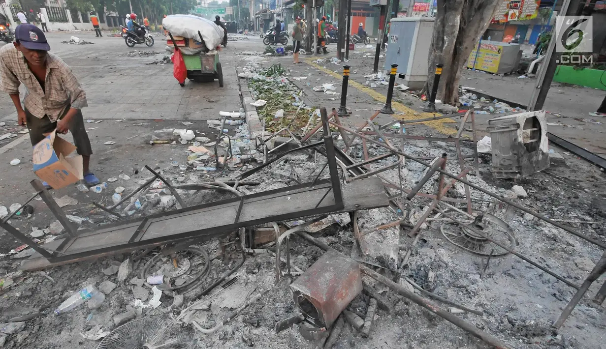 Seorang pria mencari besi di antara sisa barang yang dibakar oleh massa aksi 22 mei di kawasan Sabang, Jakarta, Kamis (23/5/2019). Massa yang ricuh di depan Kantor Bawaslu dipukul mundur oleh polisi hingga berhamburan ke sejumlah titik dekat lokasi. (Liputan6.com/Herman Zakharia)