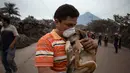 Seorang warga memeluk anjingnya setelah menyelamatkannya di dekat Volcan de Fuego, atau "Gunung Api Api," di Escuintla, Guatemala (4/6). Puluhan orang tewas akibat bencana tersebut. (AP Photo/Luis Soto)