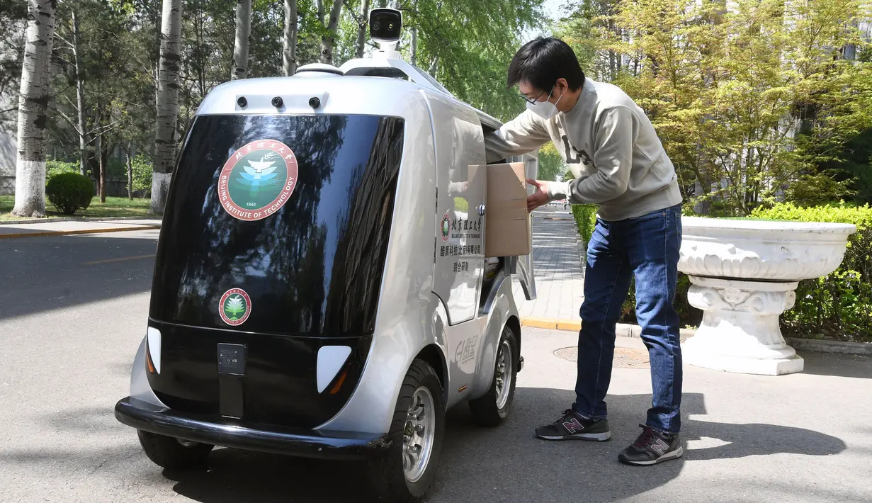 Seorang pria mengambil barang dari mobil pengiriman tanpa awak di Institut Teknologi Beijing, Beijing, China, Senin (6/4/2020). Mobil pengiriman tanpa awak berteknologi 5G ini juga mampu mengenali informasi wajah dan melakukan pengiriman tanpa bersentuhan. (Xinhua/Ren Chao)