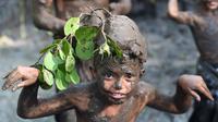 Seorang bocah berpose saat tradisi mandi lumpur atau mebuug-buugan di Desa Kedonganan, Denpasar, Bali, Jumat (8/3). Tradisi ini diadakan sehari setelah Hari Raya Nyepi. (Sonny Tumbelaka/AFP)