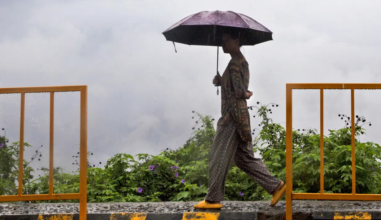 Seorang wanita memegang payung dan berjalan saat hujan di Kohima, Nagaland, India, Senin (16/5/2022). Delapan orang tewas akibat banjir dan tanah longsor yang dipicu oleh hujan lebat di wilayah timur laut India. (AP Photo/Yirmiyan Arthur)