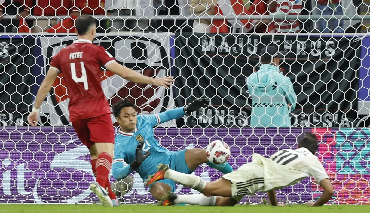 Penjaga gawang Timnas Indonesia, Ernando Ari Sutaryadi (tengah) berhasil memblok sundulan penyerang Timnas Irak Mohanad Ali pada laga pertama Grup D Piala Asia 2023 Qatar di Stadion Ahmad bin Ali, Al-Rayyan, Doha, Senin (15/ 1).  /2024).  Momen offside sempat dipermasalahkan timnas Indonesia sebelum pemain Irak Osama Rashid berhasil mencetak gol.  (AFP/Karim Jaafar)
