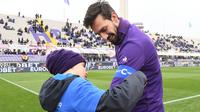 Foto pada tanggal 25 Februari 2018, seorang anak laki-laki memberi ban kapten kepada pemain Fiorentina, Davide Astori sebelum pertandingan Liga Italia di Florence. Davide Astori meninggal pada usia 31 tahun. (AFP Photo/Claudio Giovannini)