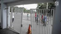 Warga yang berolahraga mengamati kerusakan pintu masuk zona 9 Stadion Utama Gelora Bung Karno, Jakarta, Minggu (18/2). Ratusan Jakmania yang tak memiliki tiket final Piala Presiden 2018 memaksa masuk stadion hingga pintu jebol (Liputan6.com/Faizal Fanani)