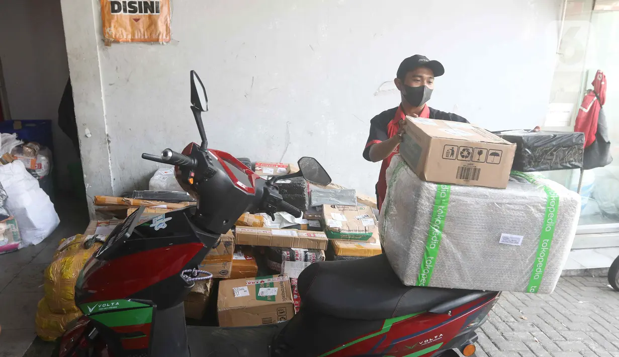 Kurir menaikkan paket untuk dikirim ke atas motor listrik di salah satu gerai ekspedisi jasa di kawasan Jakarta, Senin (5/9/2022). Selain untuk mengikuti anjuran pemerintah, penggunaan motor listrik pada kurir di perusahaan ekspedisi jasa tersebut bertujuan untuk menekan biaya operasional di tengah kenaikan harga bahan bakar minyak (BBM). (Liputan6.com/Herman Zakharia)