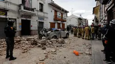 Petugas penyelamat berdiri di samping mobil yang hancur oleh puing-puing setelah gempa bumi di Cuenca, Ekuador, Sabtu (18/3/2023). (AP Photo/Xavier Caivinagua)
