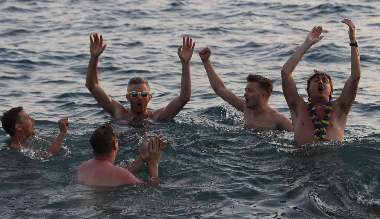 Sejumlah suporter Swedia berpesta di sekitar Pantai Sochi, Jumat (22/6/2018). Para suporter bersiap untuk menyaksikan laga Piala Dunia 2018 antara Swedia melawan Jerman. (AFP/Rebecca Blackwell)