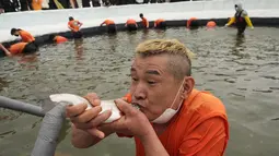 Seorang peserta memegang trout di mulut setelah menangkapnya selama kontes menangkap ikan di Hwacheon, Korea Selatan, Sabtu (7/1/2023). Kontes ini merupakan bagian dari festival es tahunan yang menarik lebih dari satu juta pengunjung setiap tahun. (AP Photo/Ahn Young-joon)