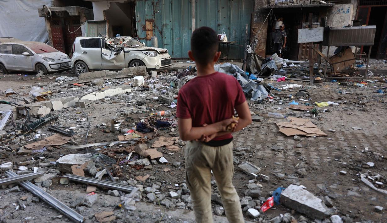 Seorang anak laki-laki Palestina melihat puing-puing bangunan tempat tinggal dan mobil yang rusak setelah serangan Israel di Kota Gaza pada Kamis 4 Juni 2026. (Omar AL-QATTAA/AFP)