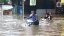Warga membawa motor melintasi banjir yang merendam jalan Raya KH Hasyim Ashari, Ciledug ,Tangerang, Rabu (1/1/2020). Banjir setinggi dada orang dewasa membuat jalur penghubung Tangerang ke Jakarta tersebut terputus tidak dapat dilintasi. (Liputan6.com/Angga Yuniar)