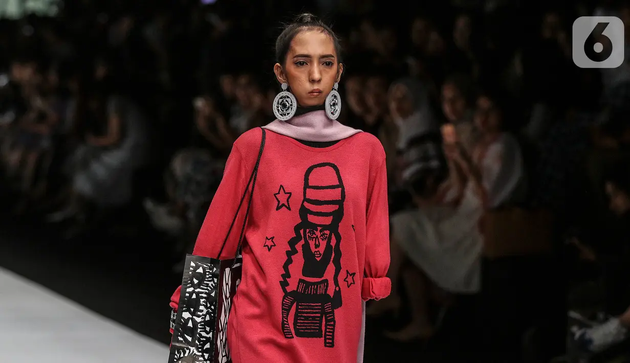 Model disabilitas mengenakan busana rancangan kolaborasi Cotton Ink x Intoart yang digawangi British Council pada Jakarta Fashion Week 2020 di Senayan, Kamis (24/10/2019). Kolaborasi ini menampilkan model disabilitas yang terdiri dari down syndrome, tuna daksa dan tuli. (Liputan.com/Johan Tallo)