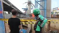 Pengemudi ojek online mengamati kondisi tiang girder Tol Bekasi-Cawang-Kampung Melayu (Becakayu) yang ambruk di Kebon Nanas, Jakarta Timur, Selasa (20/2). Tak ada penutupan jalur akibat robohnya tiang pancang tol Becakayu. (Liputan6.com/Arya Manggala)