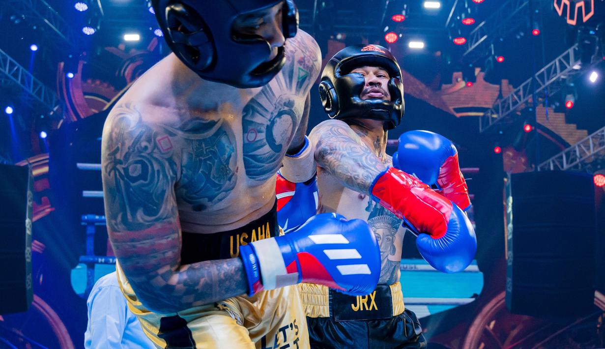 Komika, Uus (kiri), menghindari pukulan dari pemain drum Superman is Dead, Jerinx, dalam ajang tinju Holywings Sport Show (HSS) Series 3 yang berlangsung di Atlas Super Club, Bali, Minggu (10/9/2023). (Dok. Holywings)